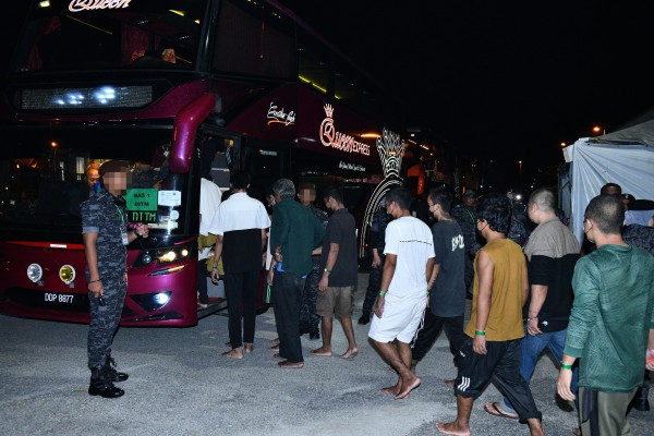 Myanmar nationals board a bus under guard in Malaysia on Tuesday ahead of their repatriation. Photo: Malaysia’s Home Ministry