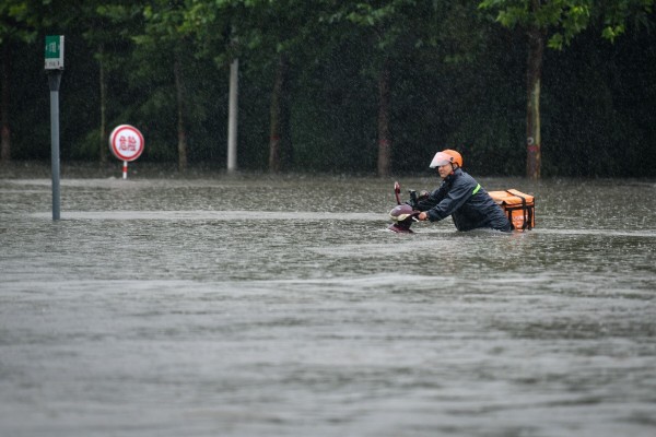 A courier wades through a waterlogged road in Zhengzhou, capital of central China's Henan Province on July 20, 2021. Photo: Xinhua