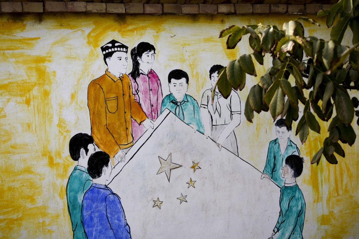 A mural depicting Uygur and Han Chinese men and women carrying the national flag of China decorates the wall of a home at the Unity New Village in Hotan, in western China's Xinjiang region. Photo: AP