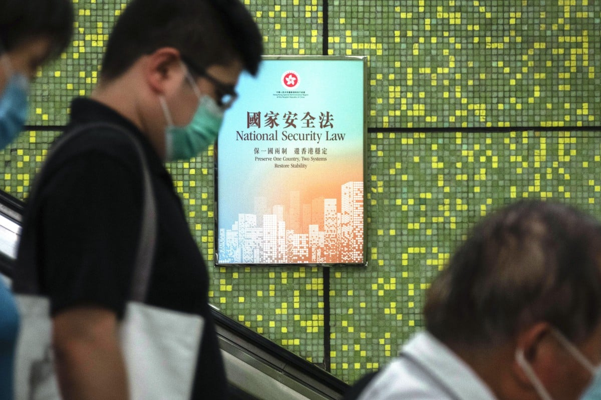 Pedestrians ride an escalator near a Government National Security Law poster in Wan Chai MTR station. Photo: Bloomberg