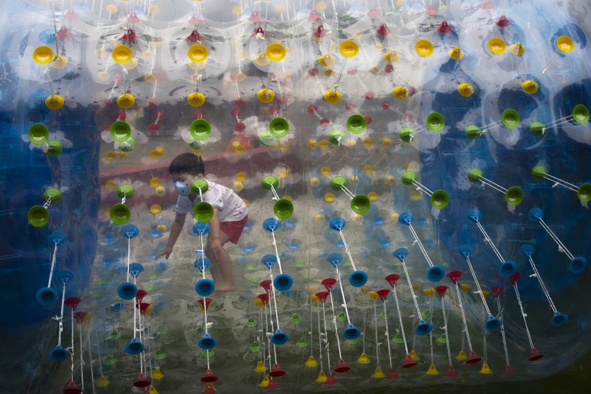 A boy wearing a face mask to protect against the coronavirus plays inside an inflatable tube at a public park in Beijing. Photo: AP