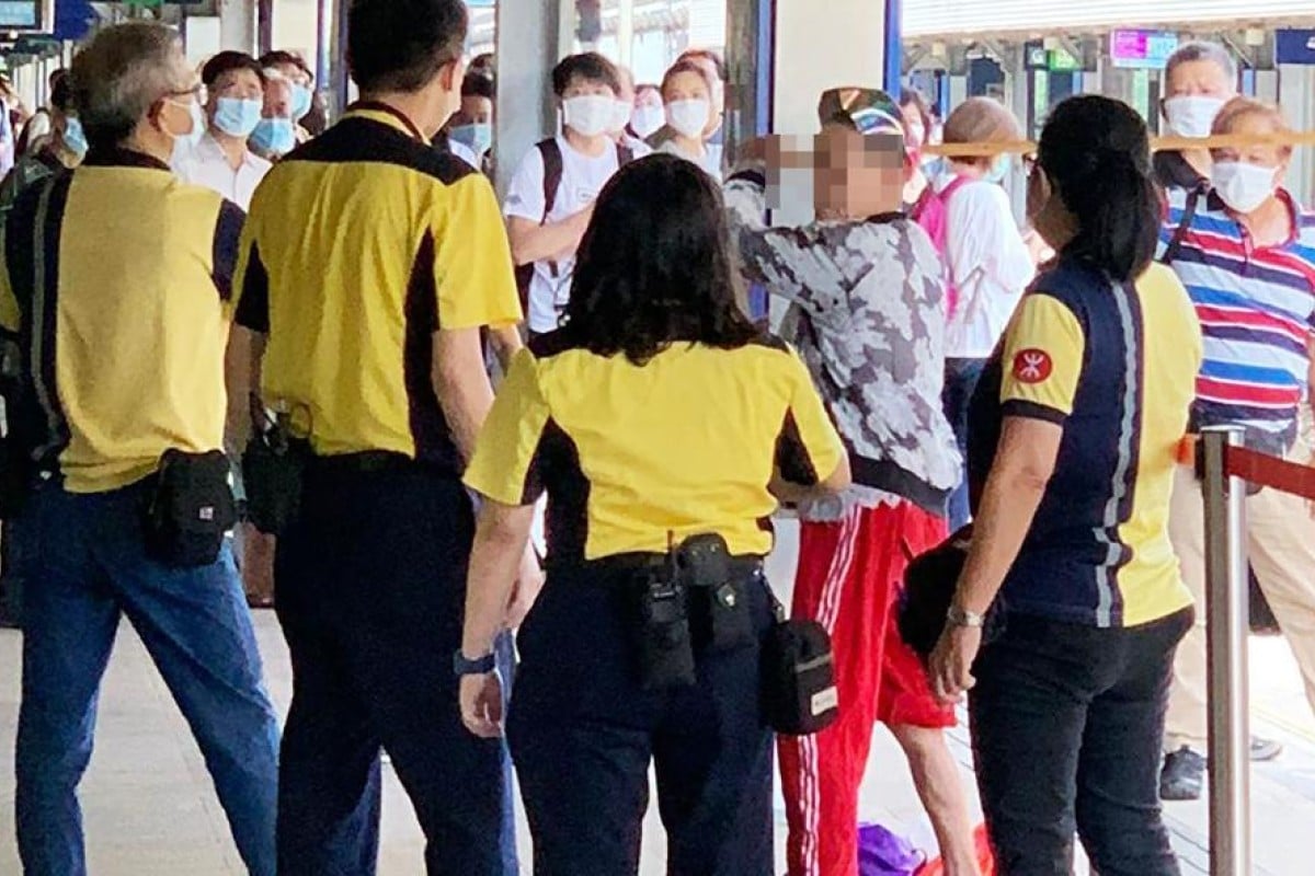 MTR staff at Tai Wan station surround a man who holds a stick over his head after refusing to wear a mask. Photo: Handout