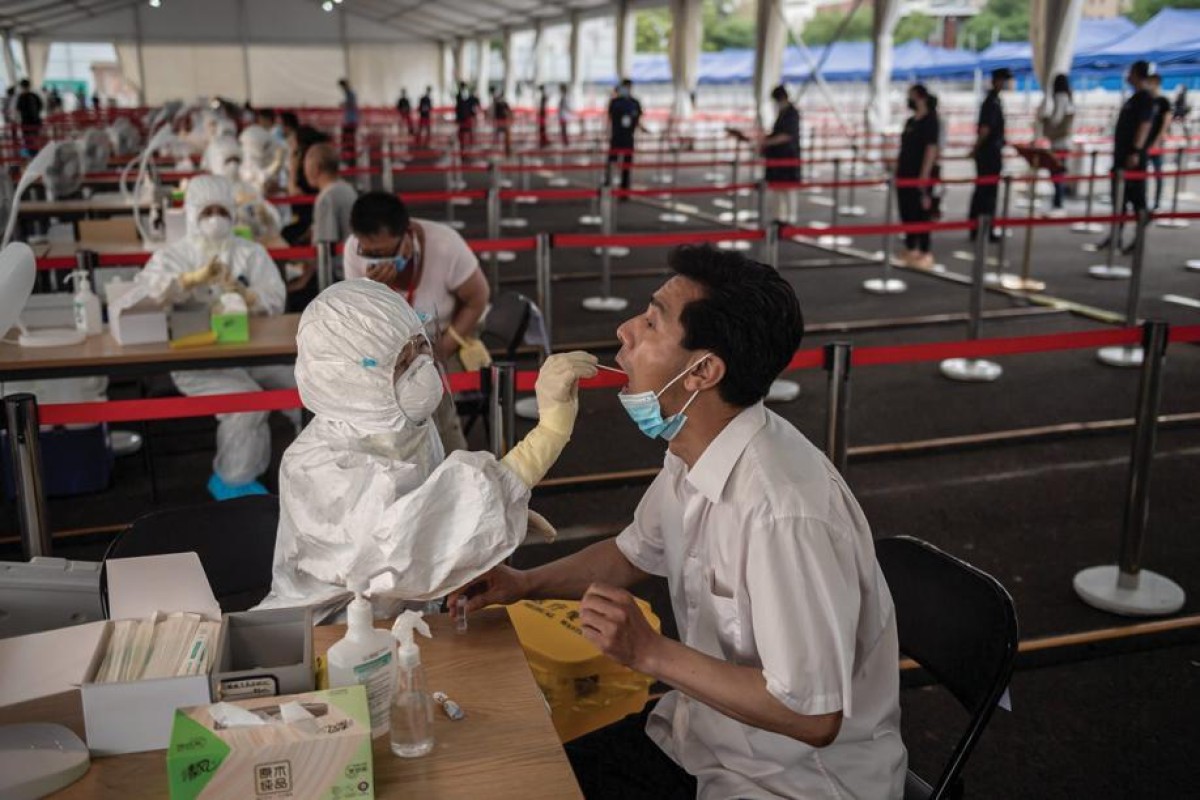A health worker wearing a protective suit, face mask and face shield takes a swab test on a man at an outdoor area during a mass testing for the COVID-19 coronavirus at the Jinrong Street testing site in Beijing. Photo: AFP