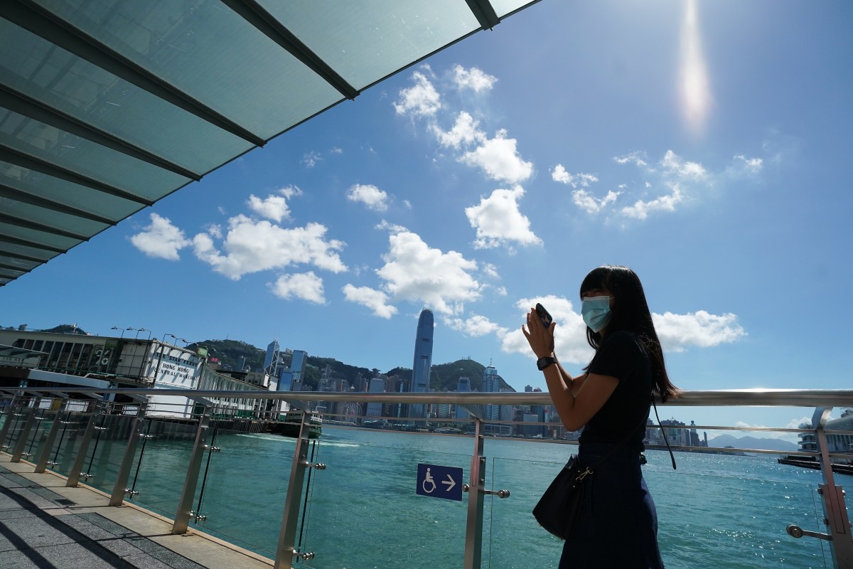 A woman takes picture in Tsim Sha Tsui during the third wave of COVID-19 outbreak in the city. Photo: SCMP / Felix Wong