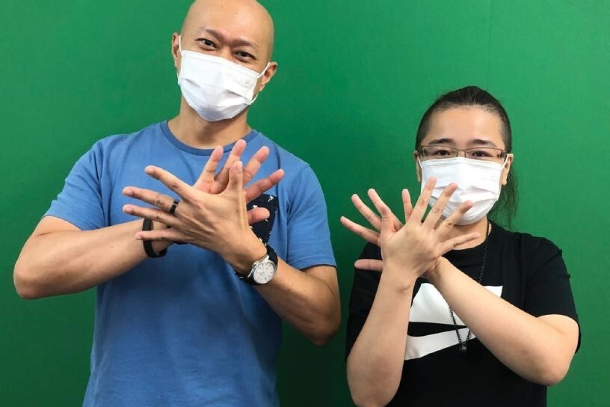 Wang Kai-fung and Kong Wan-ki, Executive Director and Master Trainer from the Hong Kong Sign Language Association (HKSLA), a non-profit organisation that promotes Hong Kong sign language and barrier-free communication, do the sign of the association. Photo: SCMP/Kelly Fung