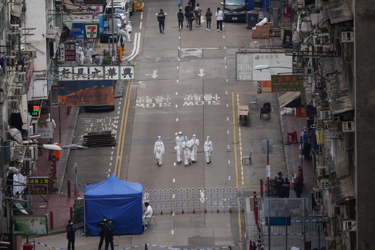 Civil servants, police and members of the disciplined services stand guard at the perimeter of the specified "restricted area" in the Yau Tsim Mong neighbourhood, to stop residents leaving the locked-down zone and to support the Covid-19 testing of all residents under the government's measure to battle against the coronavirus pandemic. Photo: SCMP / Sam Tsang