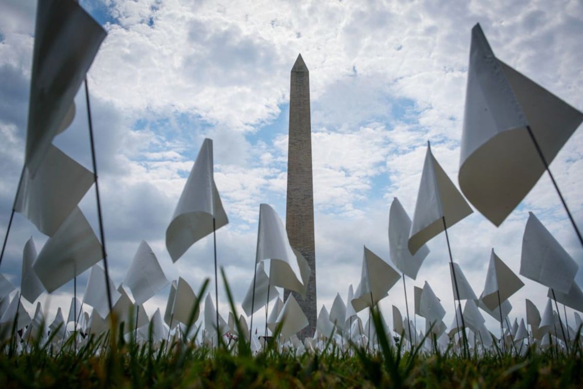 White flags are seen in front of the Washington Monument in Washington, DC. The project, by artist Suzanne Brennan Firstenberg, uses over 600,00 miniature white flags to symbolise the lives lost to Covid-19 in the US. Photo: AFP via Getty Images/TNS