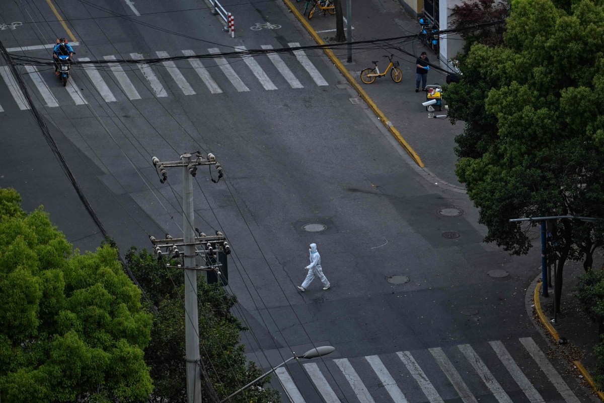 A worker wearing personal protective equipment walks down the street during a Covid-19 lockdown in the Jing’an district in Shanghai on April 12, 2022. Photo: AFP