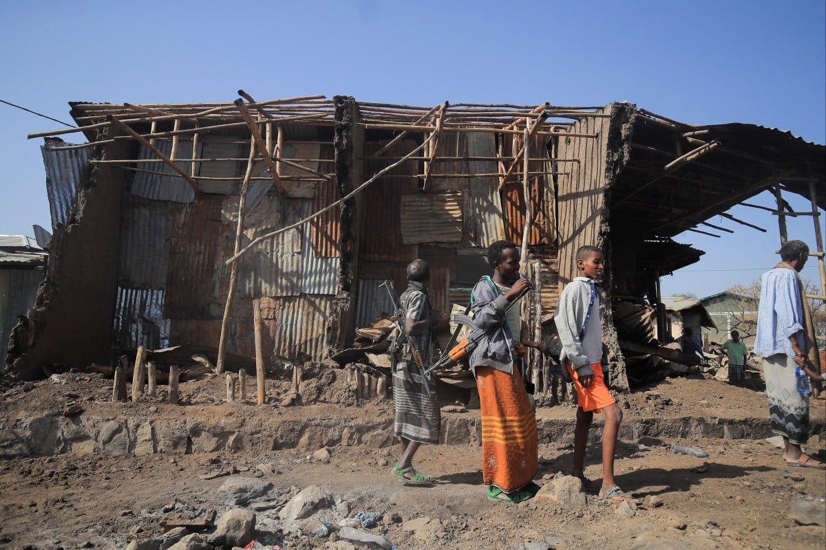 Residents and militias stand next to houses destroyed by an airstrike during the fight between the Ethiopian National Defence Forces (ENDF) and the Tigray People’s Liberation Front (TPLF) forces in Kasagita town, Afar region, Ethiopia. Picture taken on February 25, 2022. Photo: Reuters