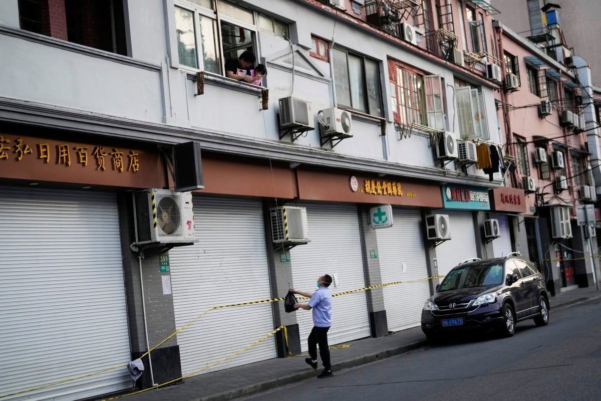 A resident ordered to stay inside their house uses a rope to pick up a bag during the coronavirus lockdown in Shanghai. Photo: Reuters
