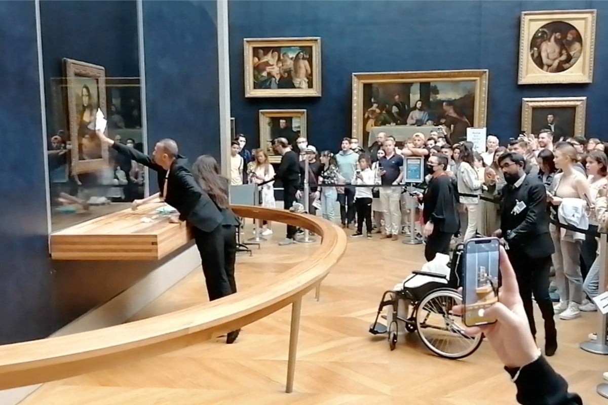 Museum staff clean the protective glass with da Vinci’s Mona Lisa behind it, after a visitor smeared it with cream, in Paris, France on May 29, 2022 in this screen grab obtained from a social media video. Twitter/@Sara_Algaba via Reuters