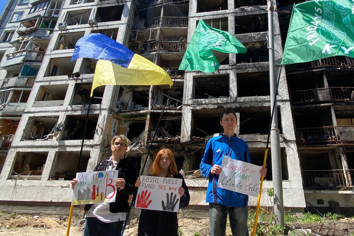Ihor Sumliennyi (right) and two other Fridays for Future Ukraine activists stage a demonstration in front of a bombed building in Ukraine. Photo: Fridays for Future Ukraine