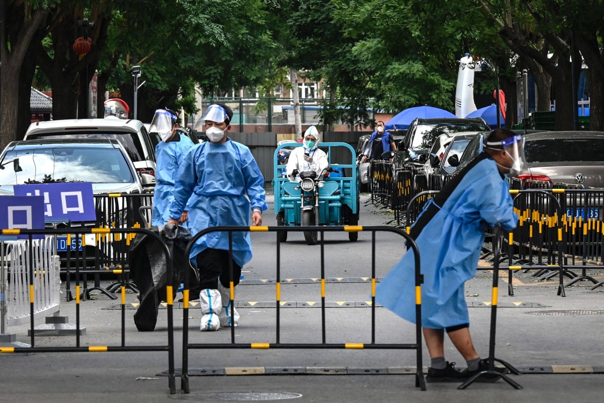 Workers and security guards in protective gear outside a locked down residential estate in Beijing. Photo: AFP