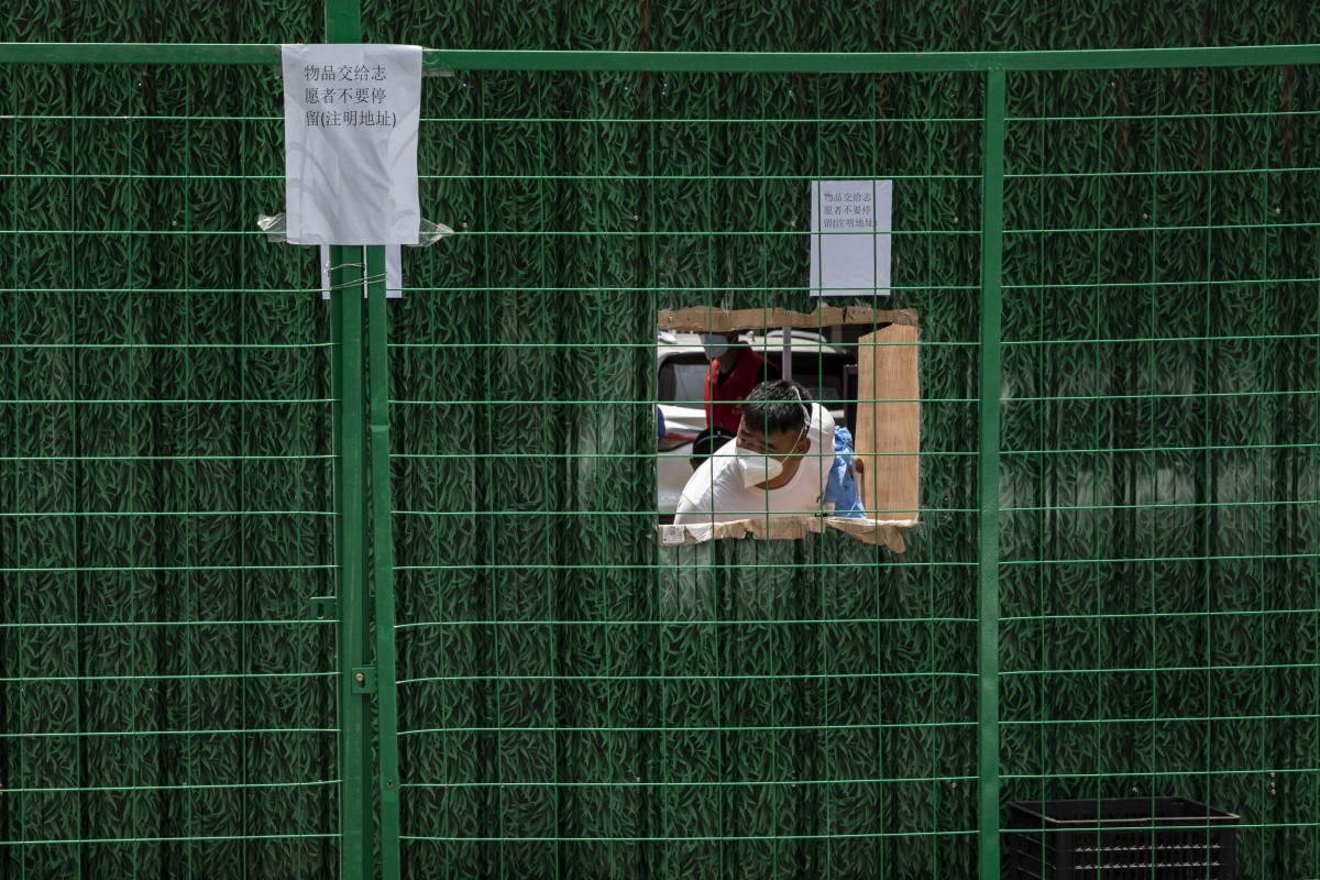 A resident behind fencing surrounding a residential neighborhood placed under lockdown due to Covid-19 in Shanghai, China on July 6. Photo: Bloomberg