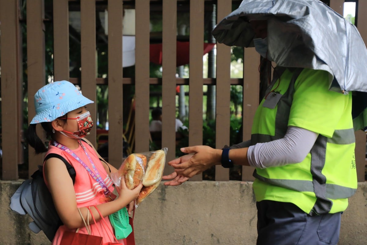 Six-year-old volunteer Boo Wu hands a bag of bread to a street cleaner in Yuen Long. Photo: Xiaomei Chen