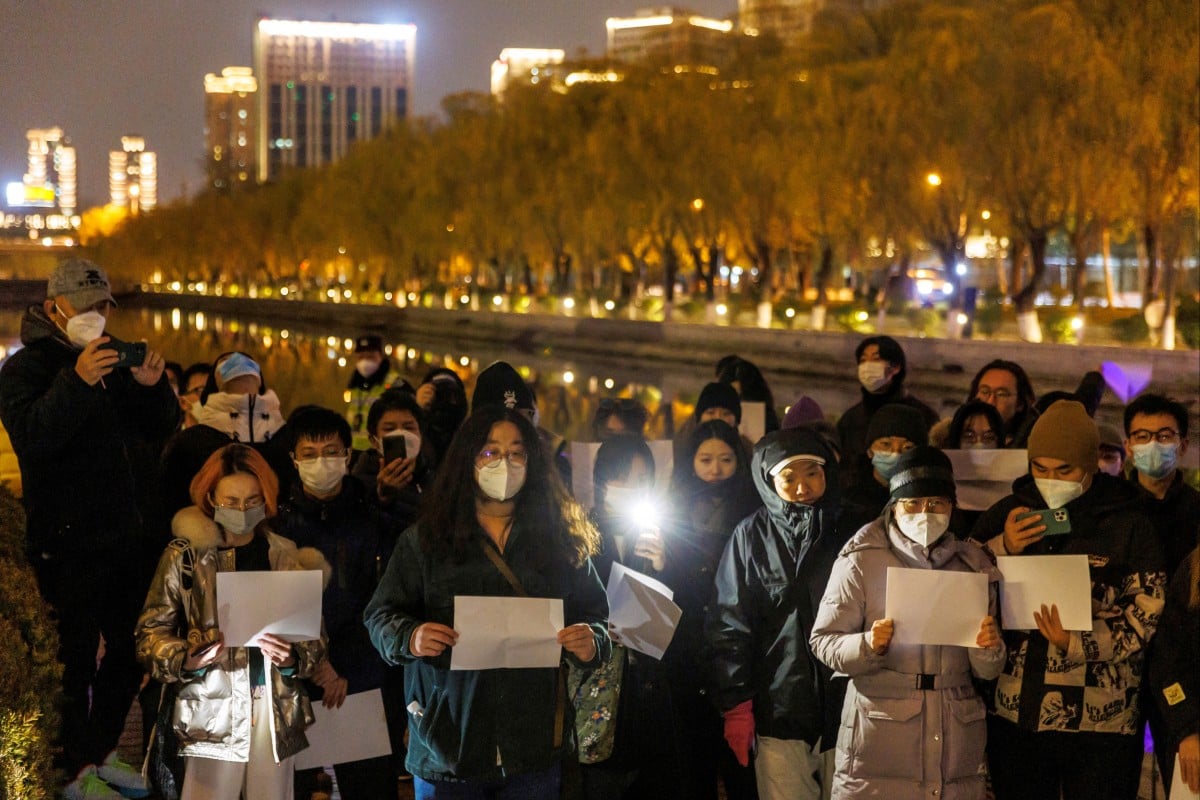 People in Beijing gather for a vigil and hold white sheets of paper during a commemoration of the victims of a fire in Urumqi. Photo: Reuters