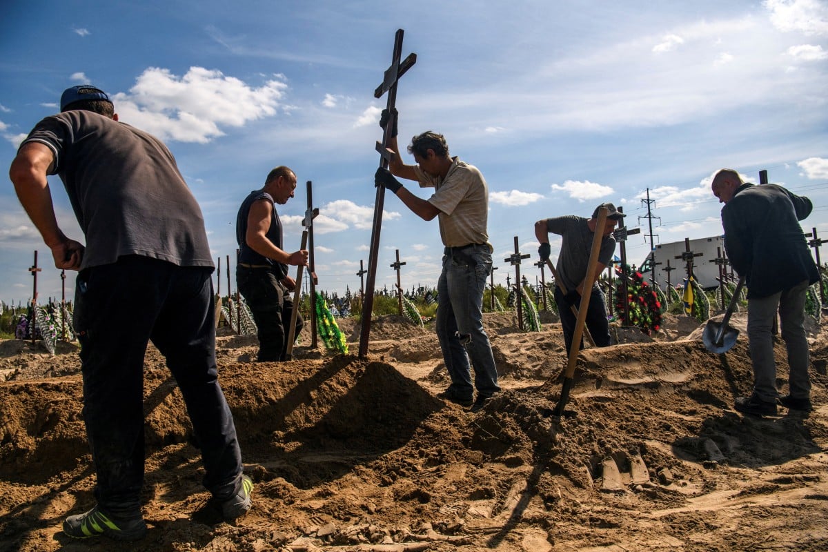 A volunteer places a cross onto a grave of one of fifteen unidentified people killed by Russian troops in the town of Bucha, Ukraine. The United Nations appealed for record funds for aid next year, as the Ukraine war and other conflicts push more people into crisis. Photo: Reuters