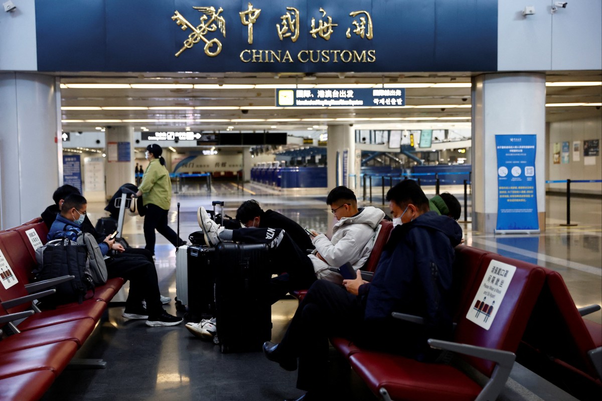 Travellers wait with their luggage at Beijing Capital International Airport. China announced it will reopen borders and abandon quarantine beginning January 8. Photo: Reuters