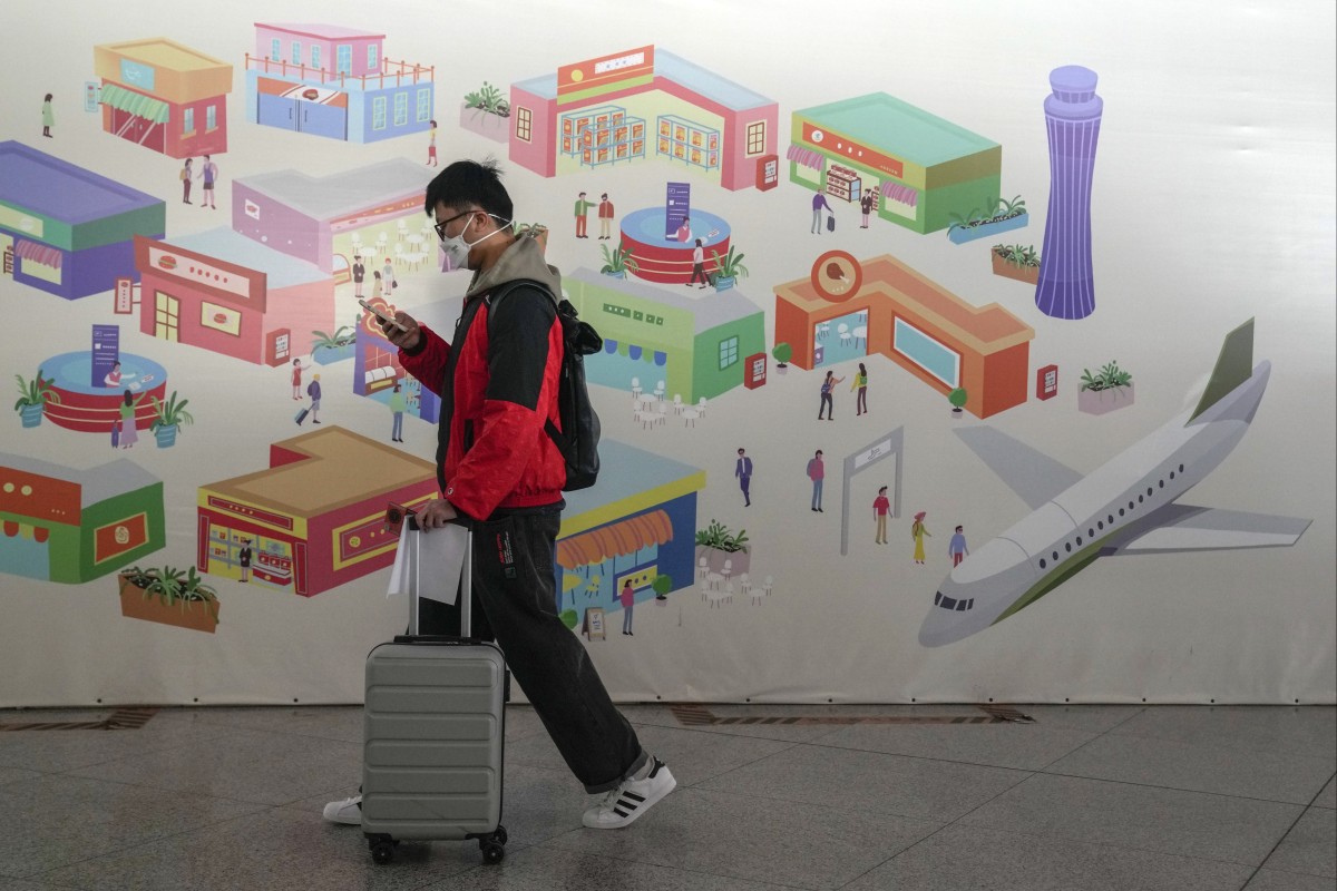A traveller wearing a face mask walks by a poster at the Beijing Capital International Airport. Moves by the US, Japan and others to mandate Covid-19 tests for passengers arriving from China reflect global concern that new variants could emerge in its ongoing explosive outbreak — and the government may not inform the rest of the world quickly enough. Photo: AP