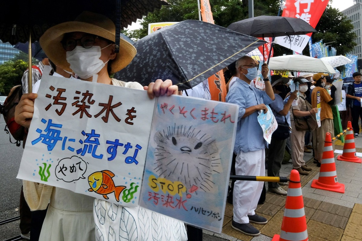A protester (L) holds signs reading “Don’t throw polluted water into the sea” (L) and “keep your promise” (C) as they take part in a rally against the Japanese government’s plan to release treated wastewater from Fukushima Daiichi power plant into the ocean, outside the prime minister’s office in Tokyo on August 22, 2023. Photo: AFP