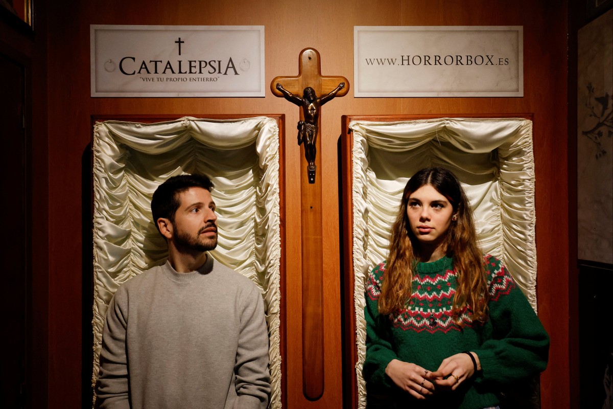 A couple of gamers, Miriam Castella and Carlos Granedo, participate in an extreme escape room, which takes place inside two coffins. Photo: Reuters