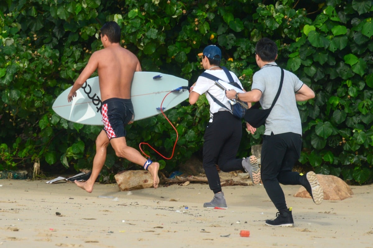 A surfer runs away from Leisure and Cultural Services Department staff trying to get his details. Photo: Antony Dickson
