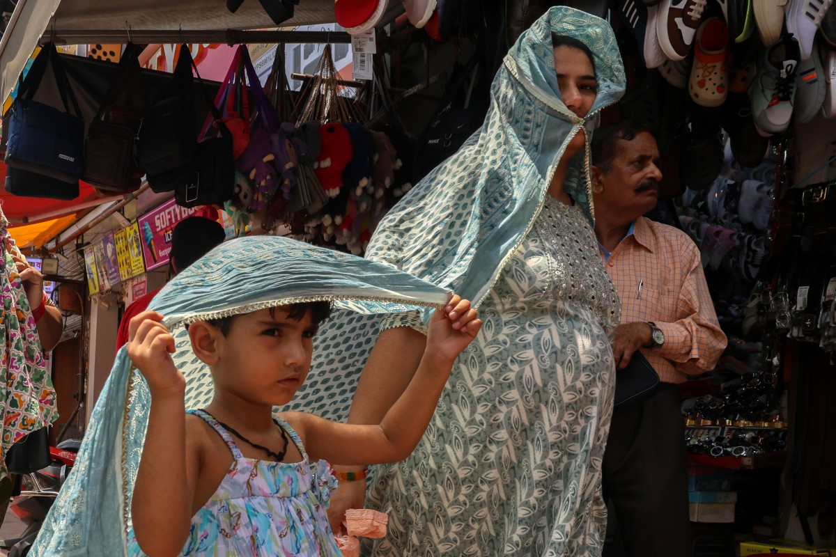 People cover themselves to avoid the sun during a hot weather day in the old quarters of Delhi, India. Photo: EPA-EFE
