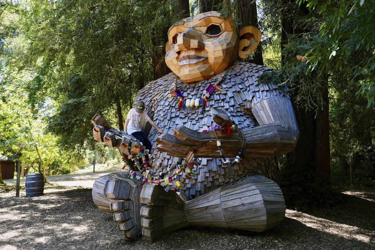 A child climbs a giant troll sculpture created by the Danish recycle artist Thomas Dambo, part of an installation of six sculptures called “Trolls Save the Humans” on display in Woodside, California. Photo: AP