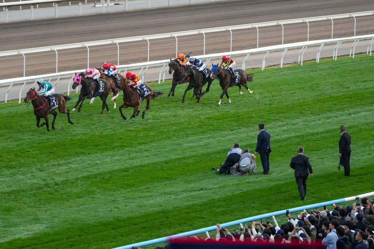 Jockey Club officials hold a man who ran onto the track down during Sunday’s Hong Kong Cup at Sha Tin. Photos: Kenneth Chan