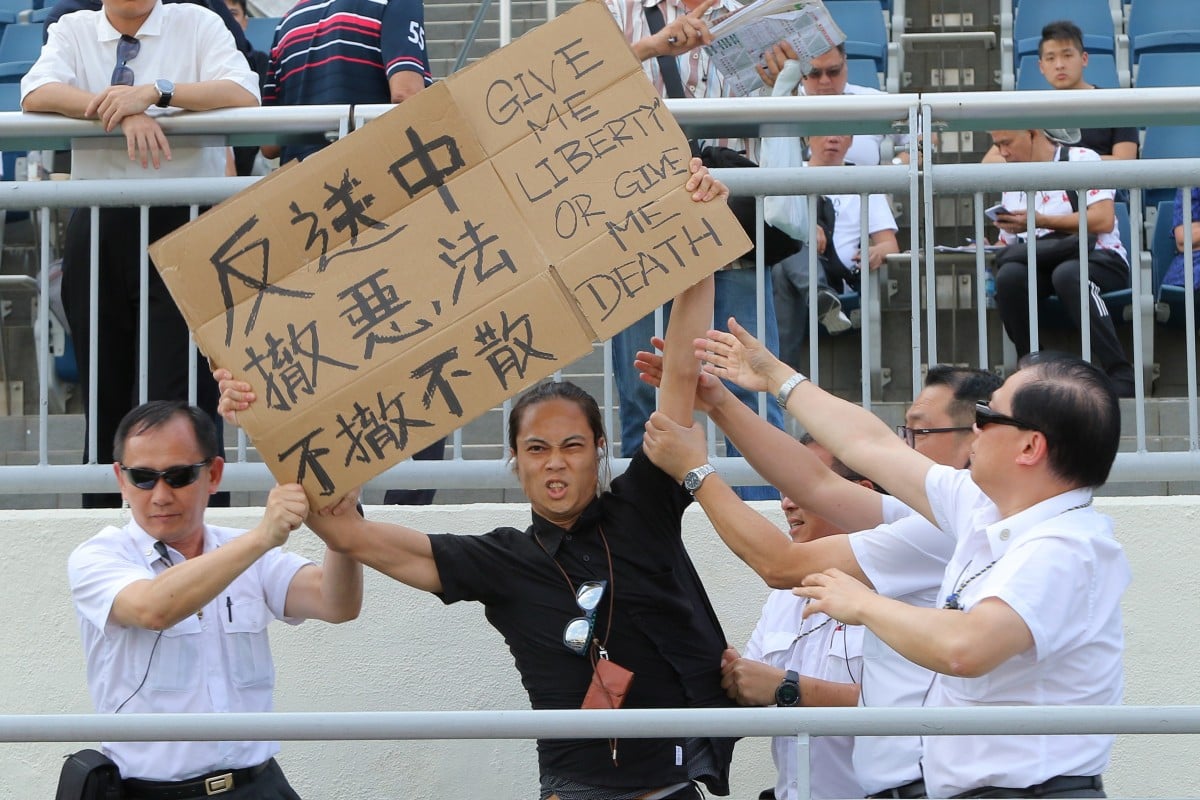 A protester holds up a sign at Sha Tin on Sunday. Photos: Kenneth Chan