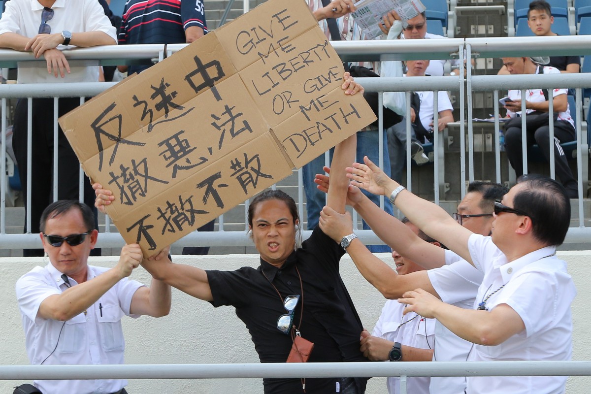 The protester is confronted by Jockey Club security at Sha Tin on Sunday. Photo: Kenneth Chan