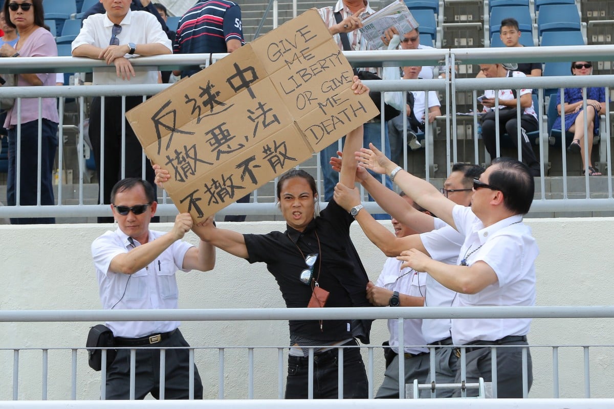 A pro-democracy protester holds up a sign at the Sha Tin races in June. Photos: Kenneth Chan