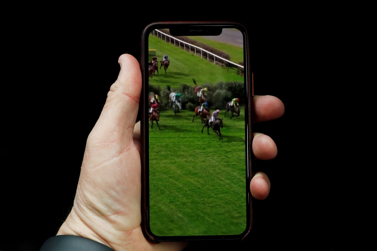 A person watches the Virtual Grand National on their phone. Photo: Reuters