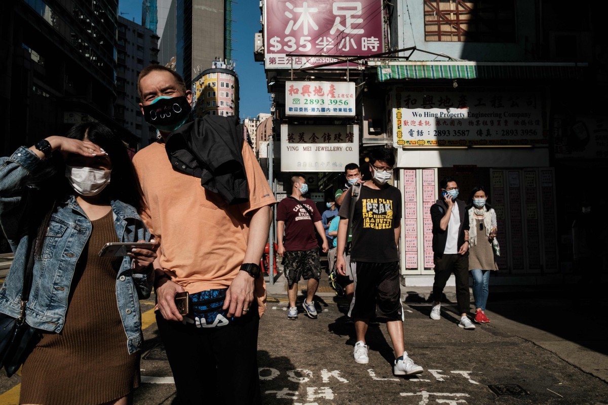 In this picture taken on on April 16, 2020 pedestrians wear face masks, as a precautionary measure against the COVID-19 coronavirus, in Hong Kong. (Photo by Anthony WALLACE / AFP)