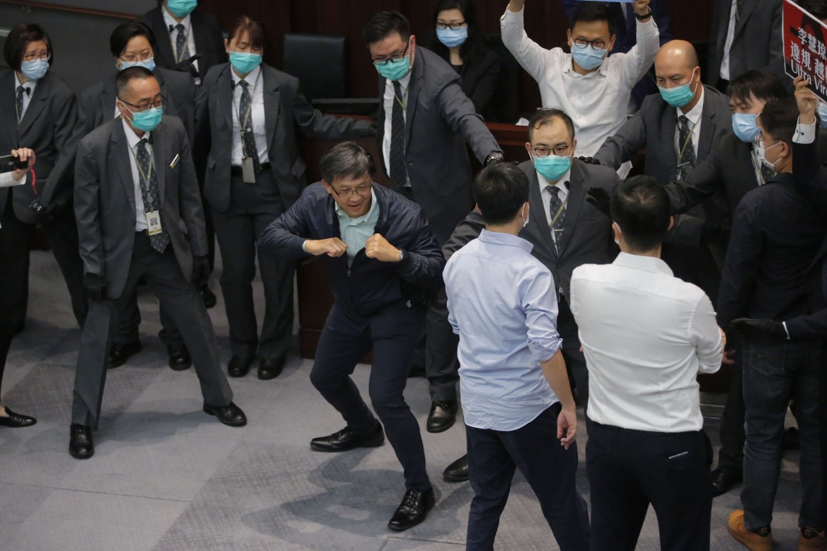 Pro-Beijing legislator Junius Ho, centre, gestures as he attempts to scuffle with pro-democracy legislators at the Legislative Council's House Committee meeting.