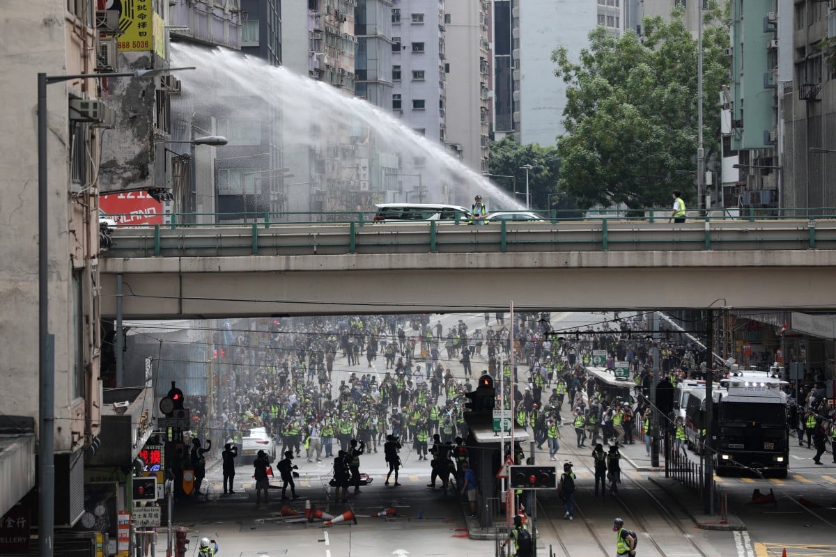 Police water canon trucks spray water to disperse protesters during a rally against the implementation of a new national security law in Causeway Bay.