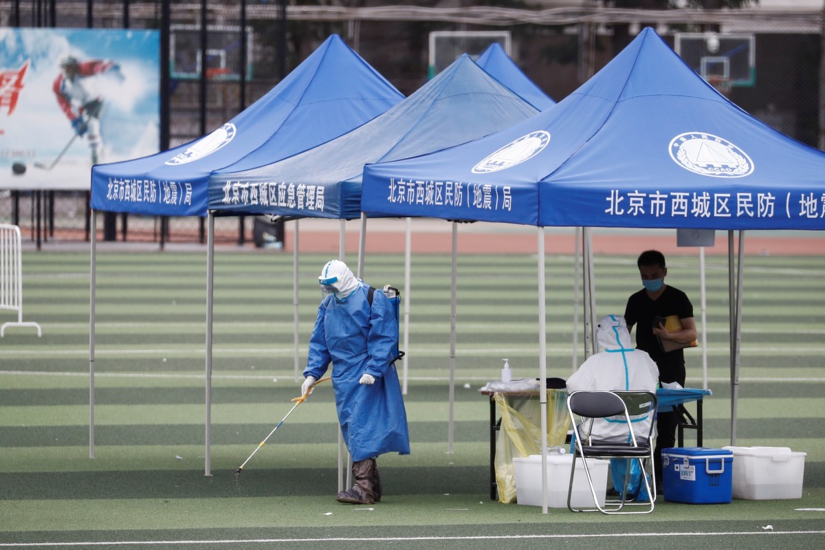 A man in personal protection gear sprays disinfectant at a testing site at the Guangan Sport Center after an unexpected spike of cases of the coronavirus disease in Beijing, China.