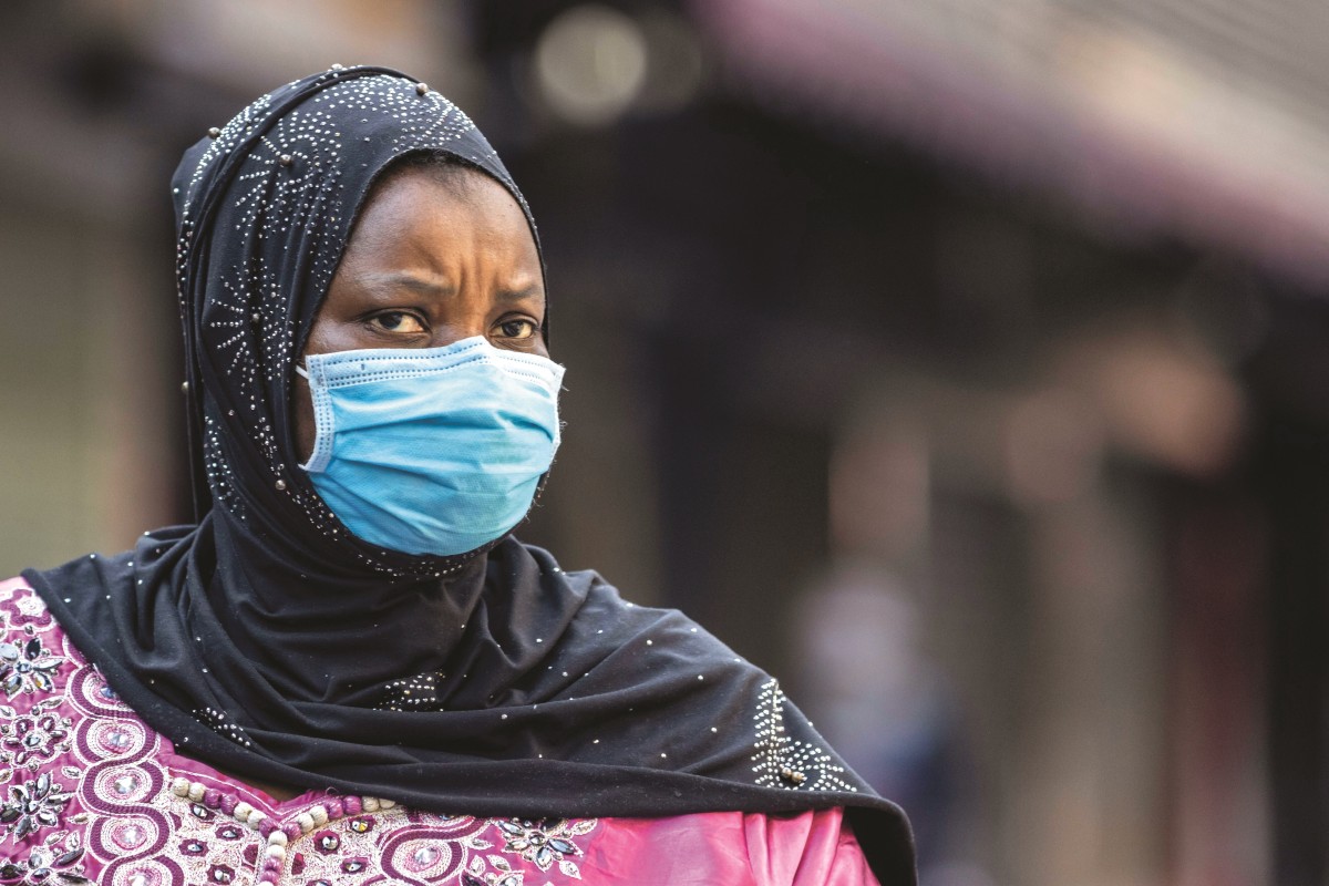 An African woman wearing a mask walks in the African Village part of Guangzhou, Guangdong province, China, 29 April 2020.