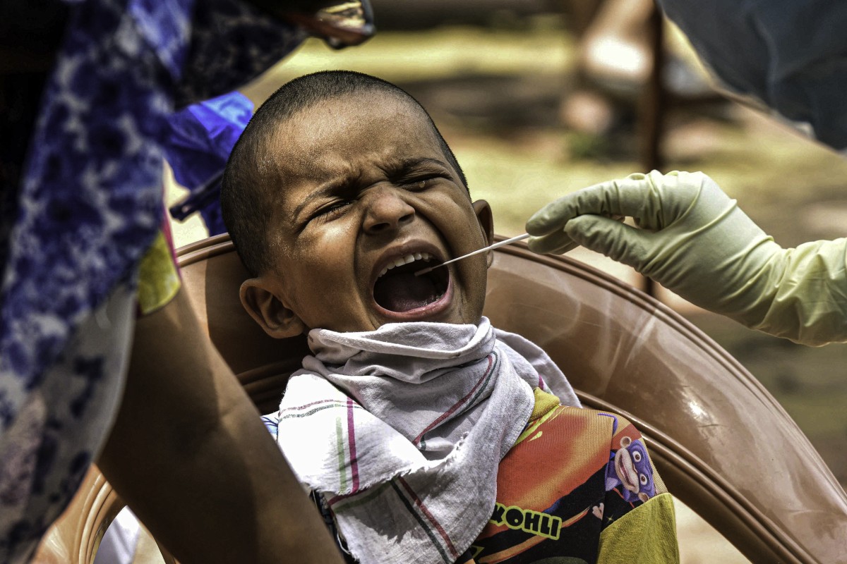 A health worker collects swab samples of a boy for Covid-19 testing inside Dharavi slum in Mumbai. Photo: Xinhua