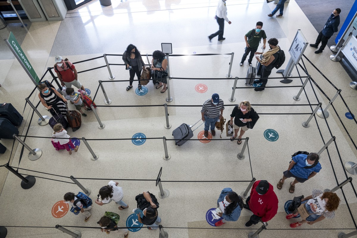 Travellers wearing protective masks stand on social distancing markers while waiting in a security line at San Francisco International Airport (SFO) in San Francisco, California, US. Photo: Bloomberg
