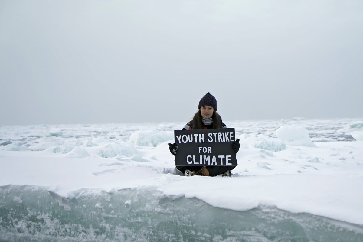 Environmental activist and campaigner Mya-Rose Craig, 18, holds a cardboard sign reading "youth strike for climate" as she sits on the ice floe in the middle of the Arctic Ocean, hundreds of miles above the Arctic Circle. Photo: Reuters