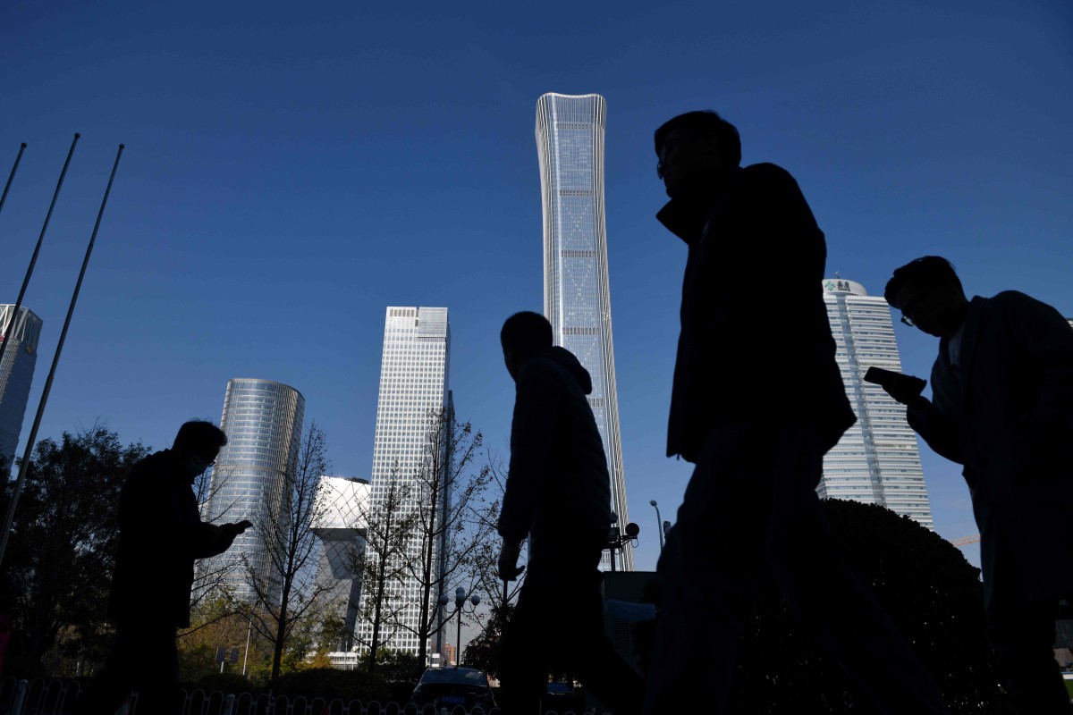 People walk past skyscrapers in the central business district in Beijing on November 24, 2020. (Photo by GREG BAKER / AFP)