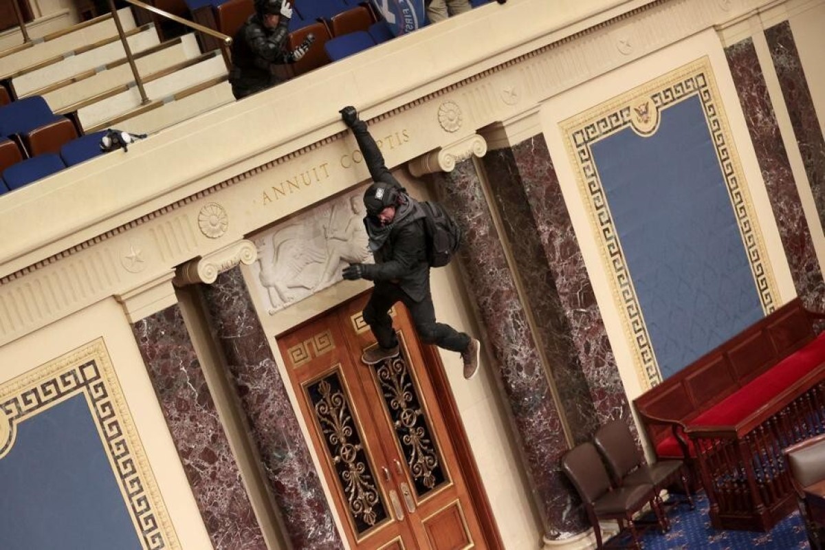 A pro-Trump rioter hangs from the balcony in the US Senate chamber on Wednesday. Photo: Getty Images/AFP