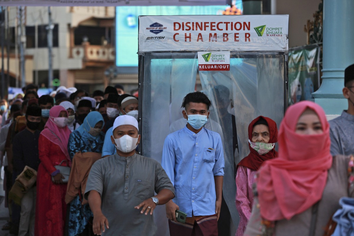 People walk through a disinfection chamber installed to curb the spread of coronavirus as they enter Al Mashun Great Mosque for Eid al-Fitr prayer in Medan, North Sumatra, Indonesia. Photo: AP