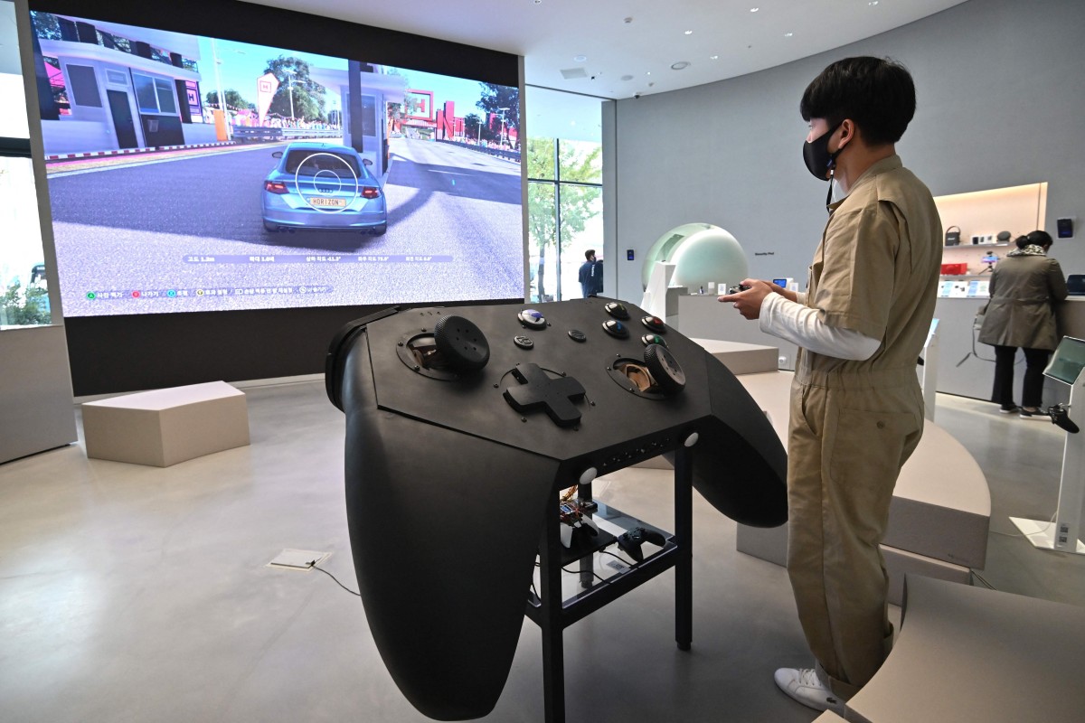 A staff member plays a game in front of an oversized mock-up of an Xbox controller at a flagship store of SK Telecom in Seoul. Microsoft unveiled a batch of new titles for Xbox at E3 on Sunday. Photo: AFP