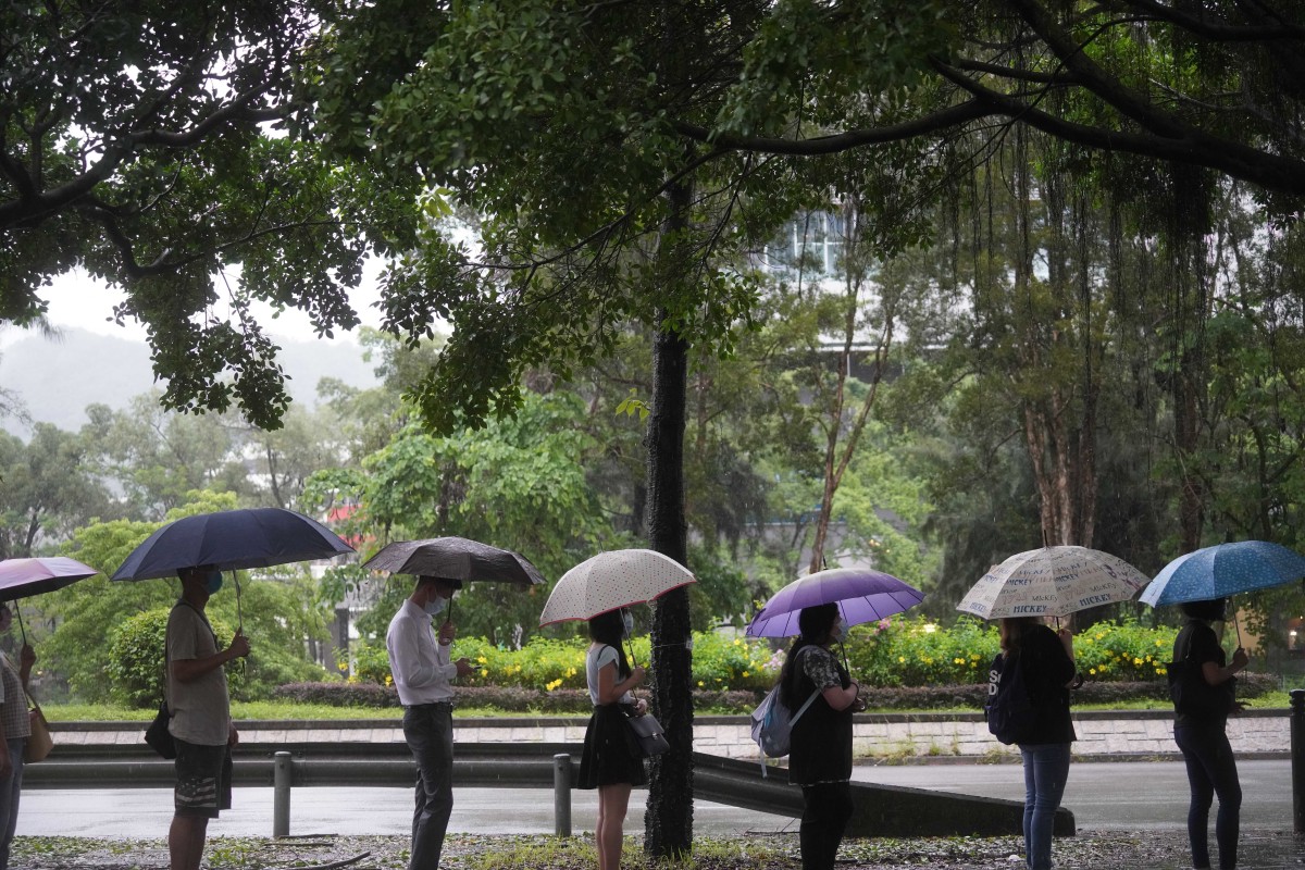 People queue on the street under heavy rain in Tai Po. Photo: SCMP/Winson Wong