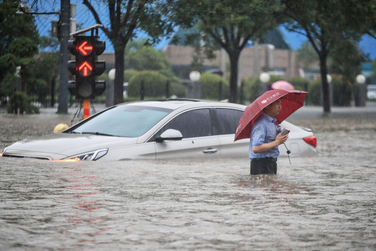A man wades past a submerged car along a flooded street following heavy rains in Zhengzhou in China's central Henan province. Photo: AFP