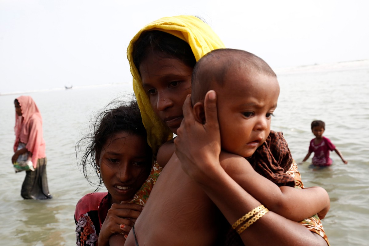 Rohingya refugee woman and children wade to the shore after crossing the Bangladesh-Myanmar border by boat through the Bay of Bengal in Teknaf.