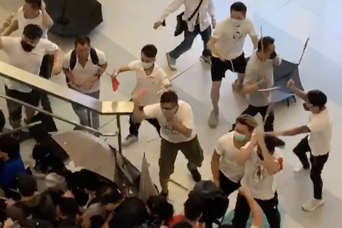 A screen grab from a video shows a group of people in white with wooden sticks chasing and assaulting passenger at the Yuen Long MTR station.