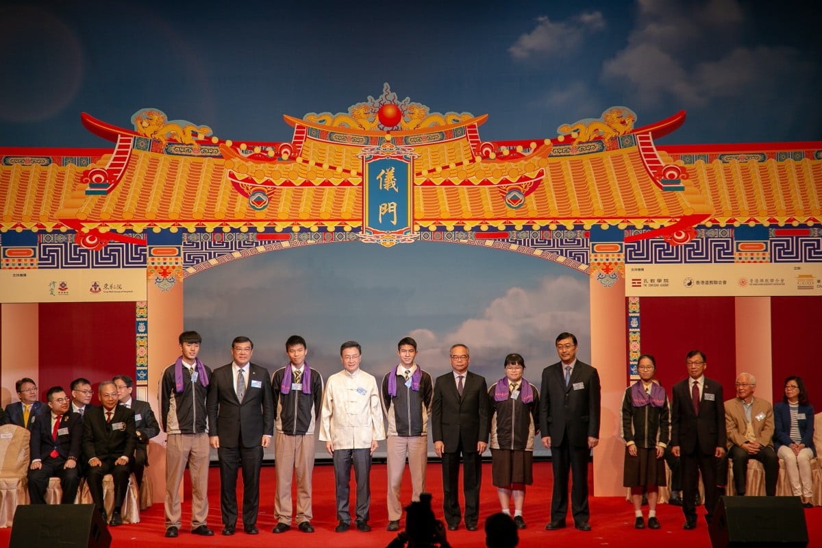 Student representatives stand on stage in front of the yi men, joined by several guest speakers.